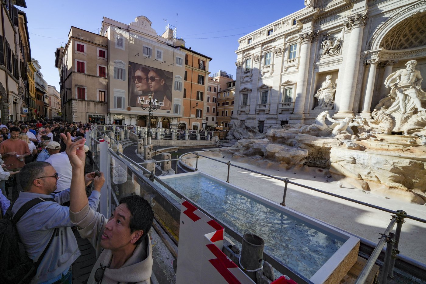 Tourists toss coins over a makeshift pool as Rome’s Trevi Fountain undergoes maintenance | iNFOnews.ca