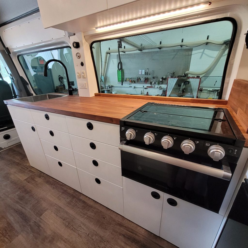 The sink and stove top inside a custom-built campervan.