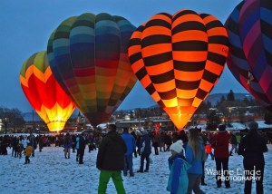 A photo of glowing hot air balloons in Vernon with a crowd and snow.