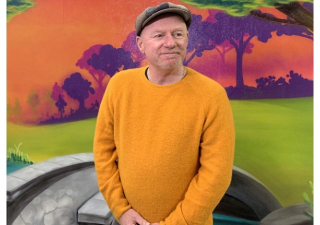 A man standing in front of a painted mural.