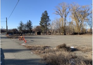 A empty property fronted by a sidewalk.