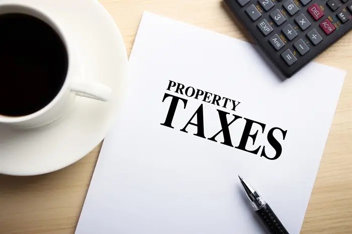 Penticton looking at 6 per cent tax increase as budget deliberations begin | iNFOnews.ca A cup of coffee and a calculator on a desk top with a piece of paper that reads 'property taxes'.