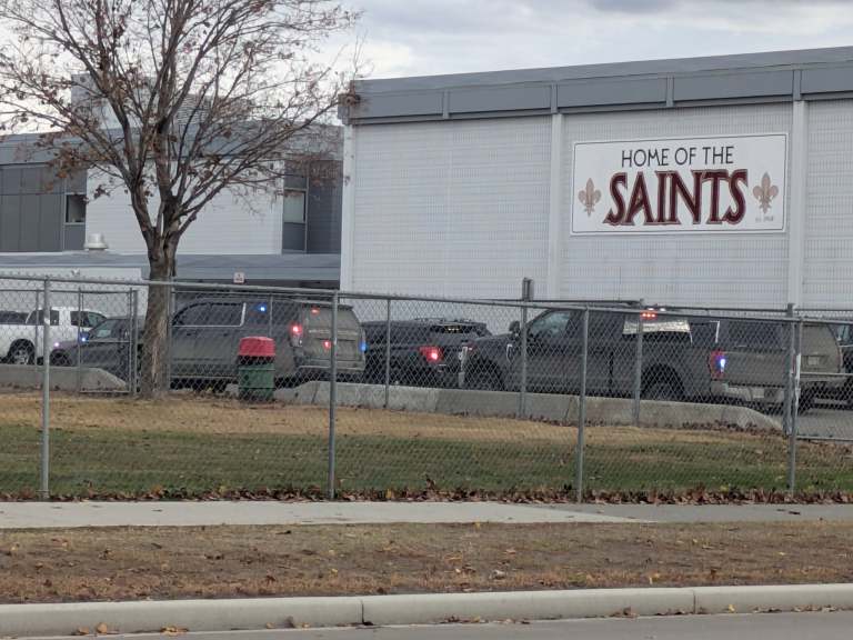 Exterior of a high school seen with multiple police vehicles in front.