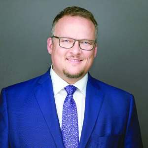 A man in a suit poses for a photo.