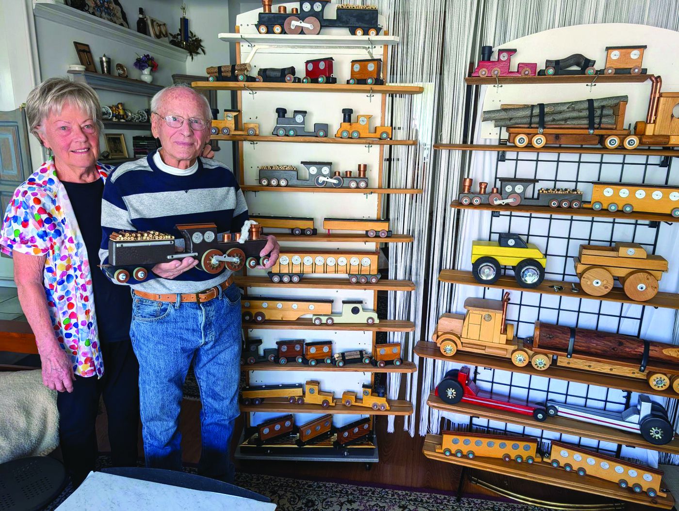 Penticton man carves new chapter at age 89 | iNFOnews.ca An elderly woman and man stand in front of a shelf full of wooden toys.