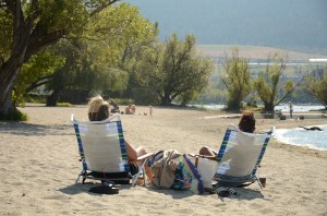 Two women sit on beach chairs on the beach.
