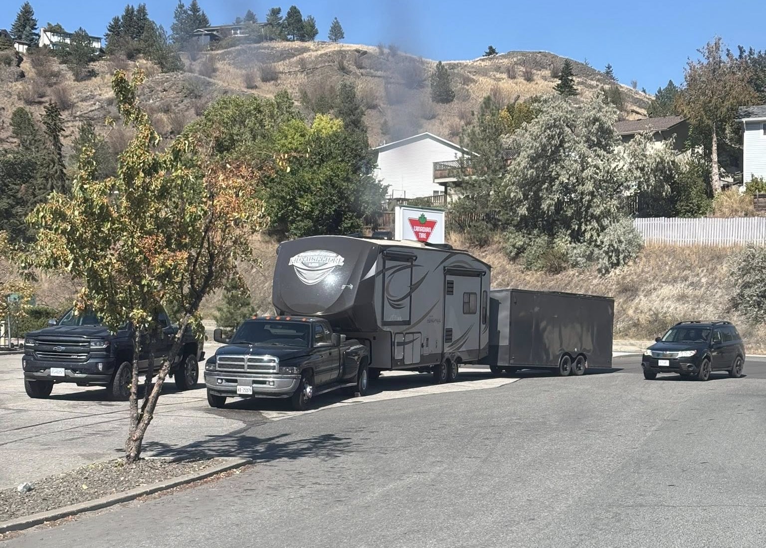 A truck parked in a lot is hooked up to a camping trailer that is hooked up to a cargo trailer.