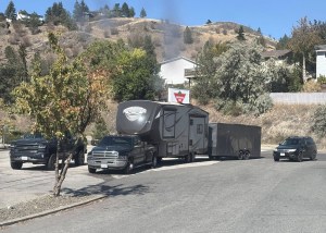 A truck parked in a lot is hooked up to a camping trailer that is hooked up to a cargo trailer.