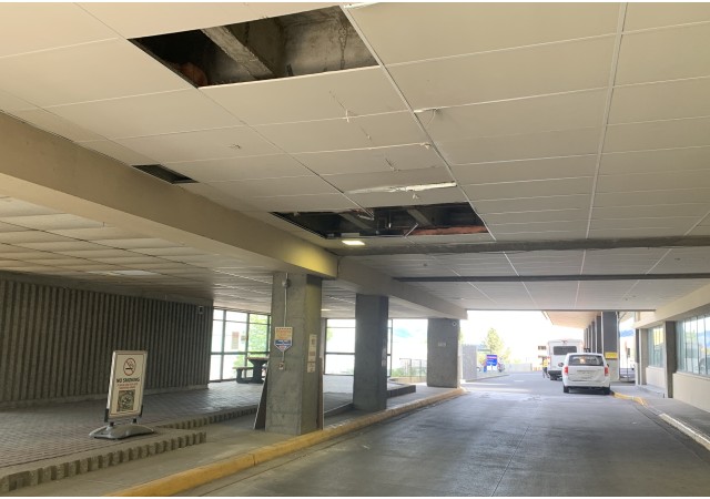 A drive-thru entrance to a hospital with a damaged awning.