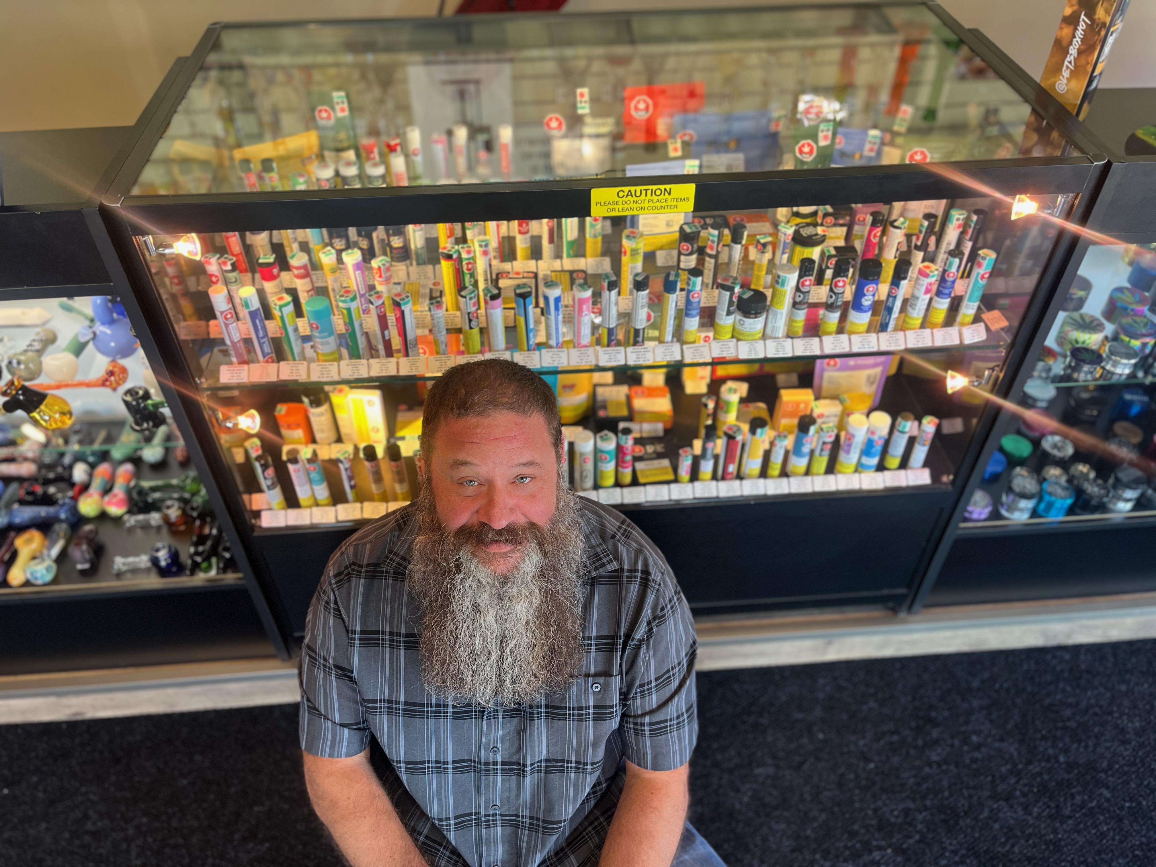 A man stands in front of a cabinet of cannabis products.