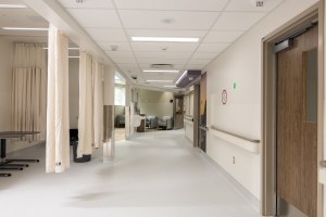 A white hallway lined with hospital rooms