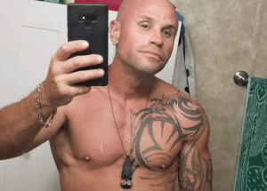 A man poses with a cell phone in front of a mirror.