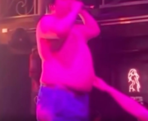 A person sticking their finger in a singer's belly button.