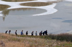 People walk along a lake shore.