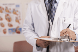 A doctor writes on a clipboard.
