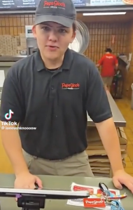 An employee ready to take an order at a pizza joint.