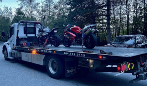 Two motorcycles on the back of a tow-truck.