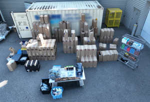 Boxes filled with cigarettes and drugs next to a shipping container.