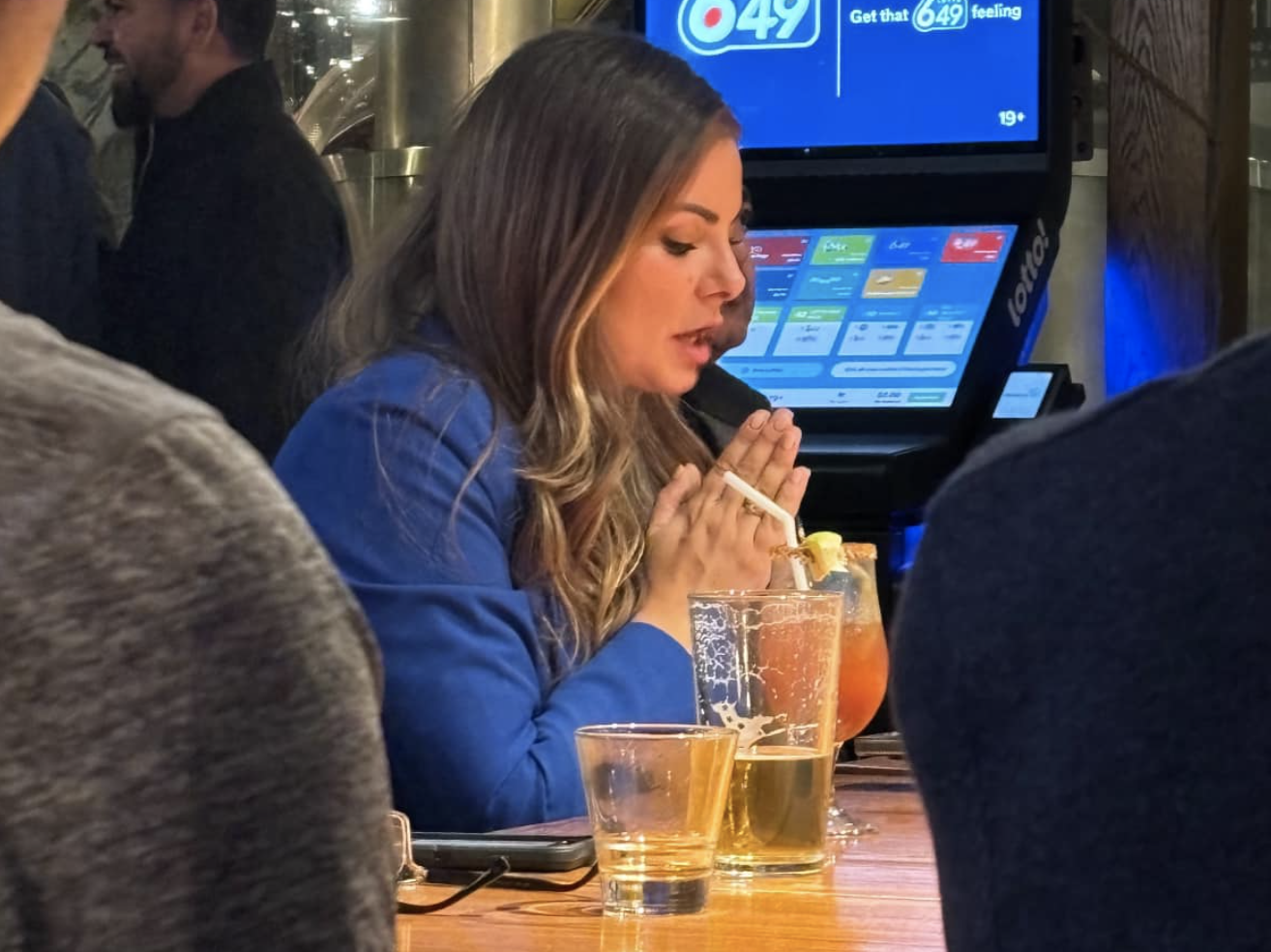 A picture of a woman praying over a Caesar cocktail.