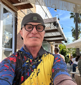 Wearing a cycling jersey, Tom Budd takes a selfie.