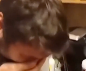 A guy covering his face laughing.