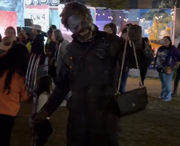 A guy in a zombie costume holding a purse.