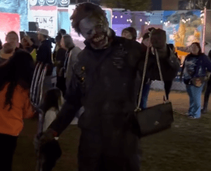 A guy in a zombie costume holding a purse.