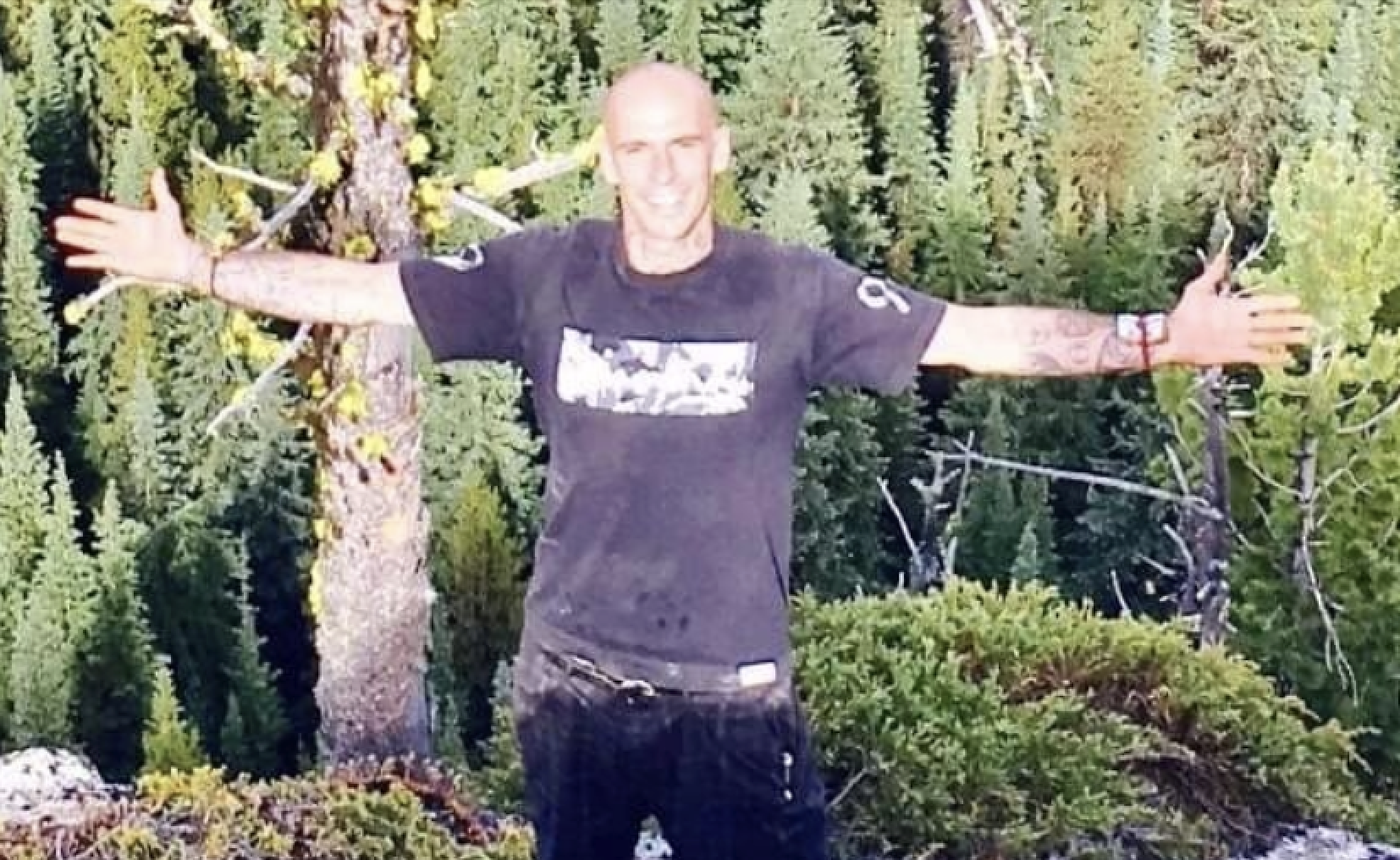 Knox Mountain arson suspect wore camouflage, armed with slingshot: Kelowna RCMP | iNFOnews.ca A man stands in a wooded area with his arms outstretched.