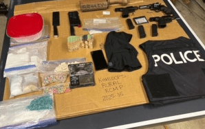 Drugs and guns laid out on a table with a police vest.