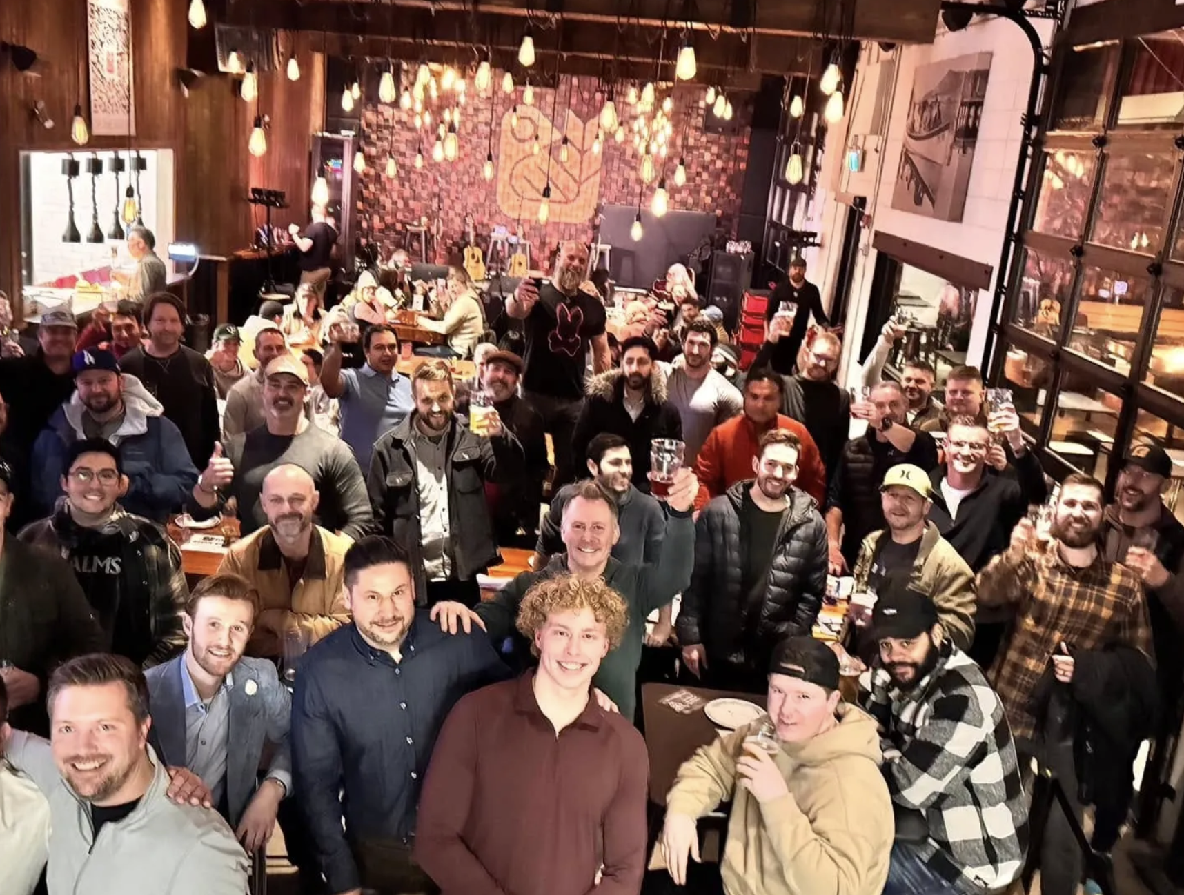A big group photo of a bunch of guys at a bar.