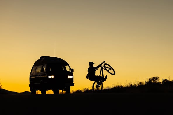 iN PHOTOS: September silhouettes captured in Kamloops, Okanagan | iNFOnews.ca A van beside a person popping a wheelie on a bike are silhouetted against a soft, golden coloured sky.