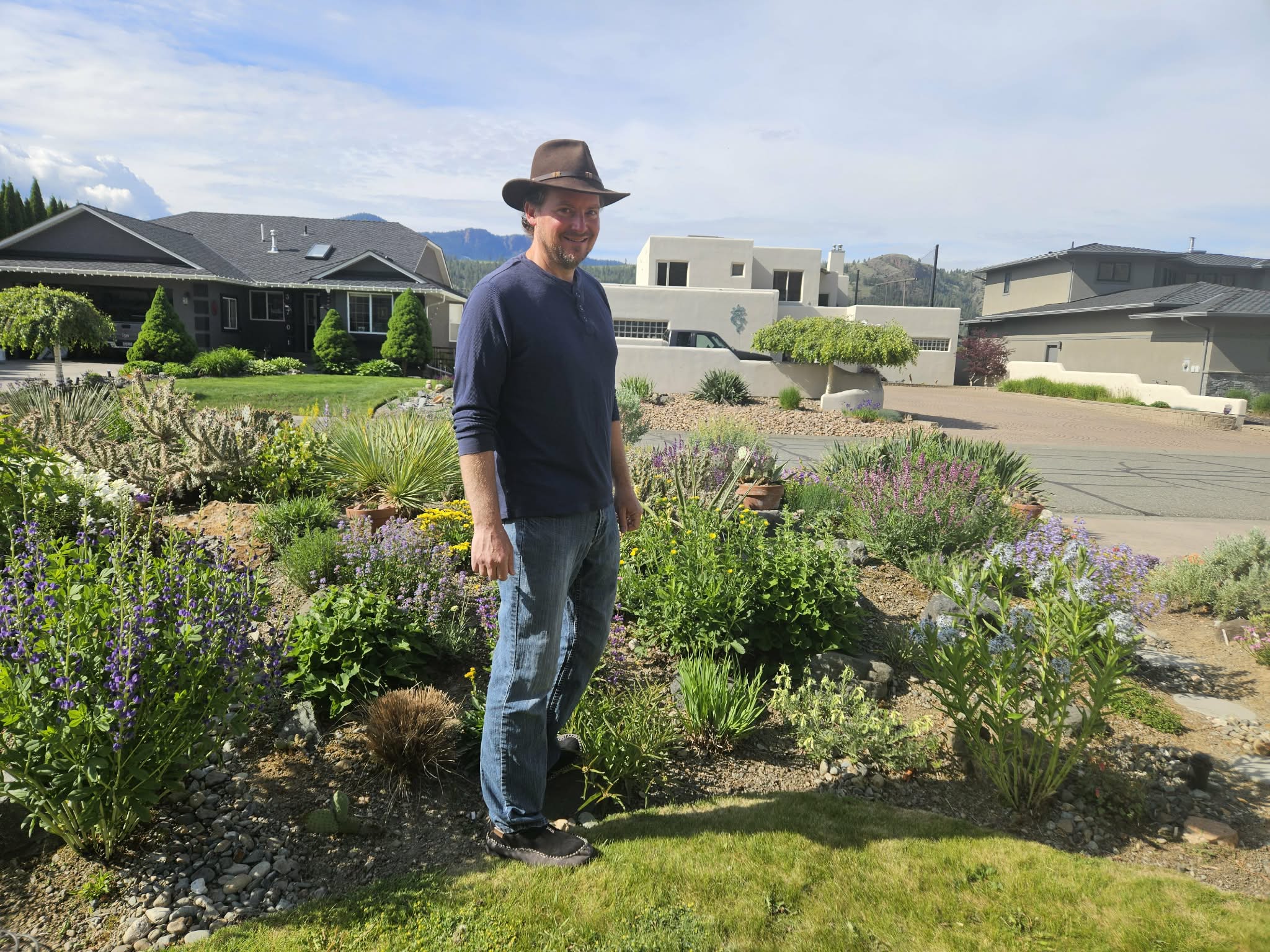 Zero water required for garden bursting with blooms in Kamloops | iNFOnews.ca A man stands next to a garden.