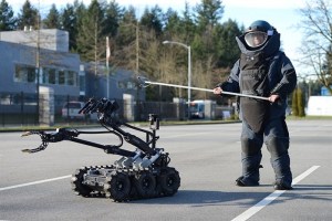 RCMP in a bomb suit with a robot beside him.