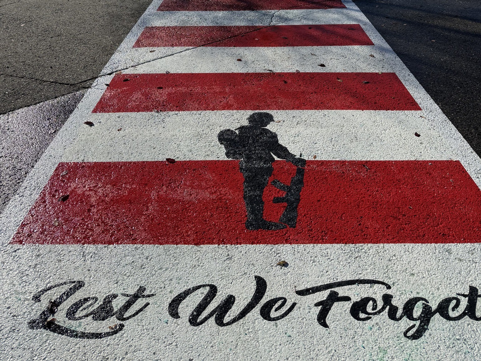 Crosswalks honour veterans in Okanagan, Nicola as Legion marks 100th anniversary | iNFOnews.ca A red and white crosswalk has a soldier and the words Lest We Forget painted on it.