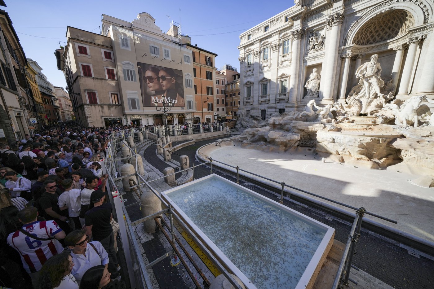 Tourists toss coins over a makeshift pool as Rome’s Trevi Fountain undergoes maintenance | iNFOnews.ca