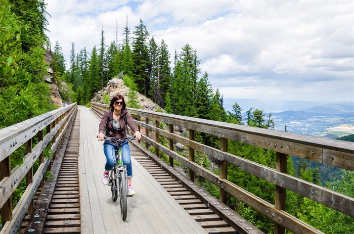 A woman rides a bicycle on a trestle bridge.
