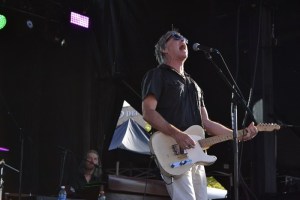 54-40 frontman Neil Osborne screaming on stage and playing guitar at an outdoor concert.
