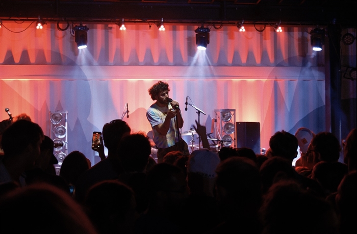 A singer lit by colourful lights performing for a crowd.