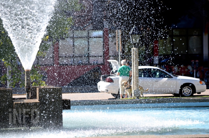 A picture of someone behind a big water fountain.