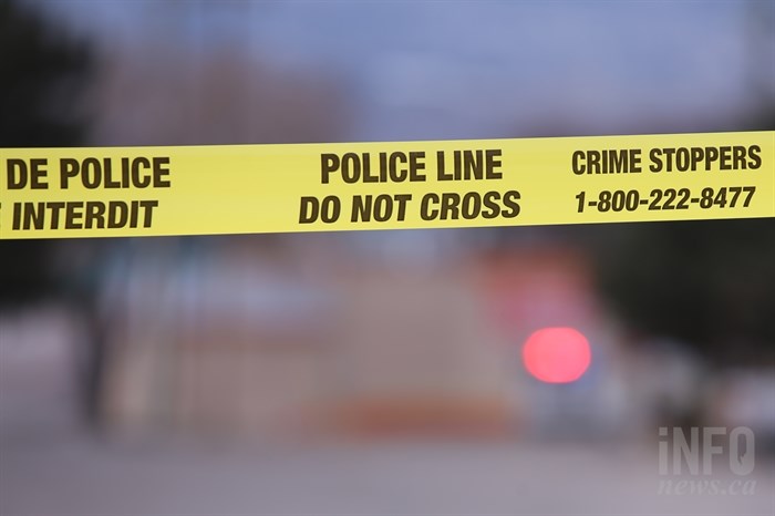 Yellow police tape with a blurry emergency vehicle in the background.