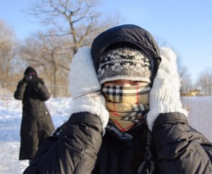 Someone wearing a scarf and mittens on a cold winter day.