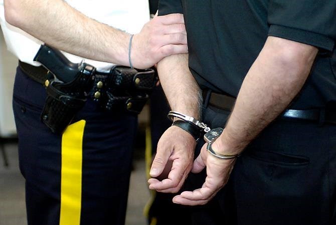 A police officer holding a man's arm who is in handcuffs, and you can't see their faces.