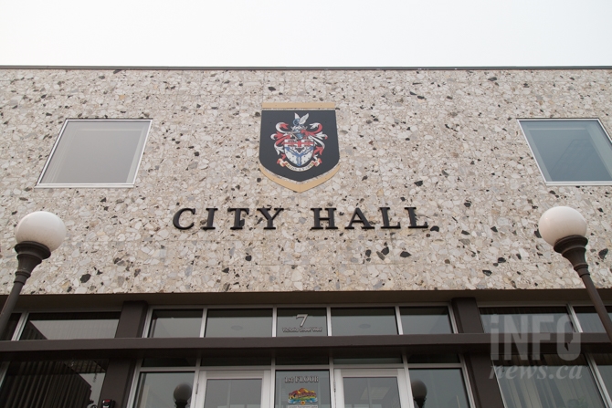 Front of a building with a coat of arms and text that reads "city hall"