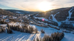 An aerial view of a village below a mountain ski resort.