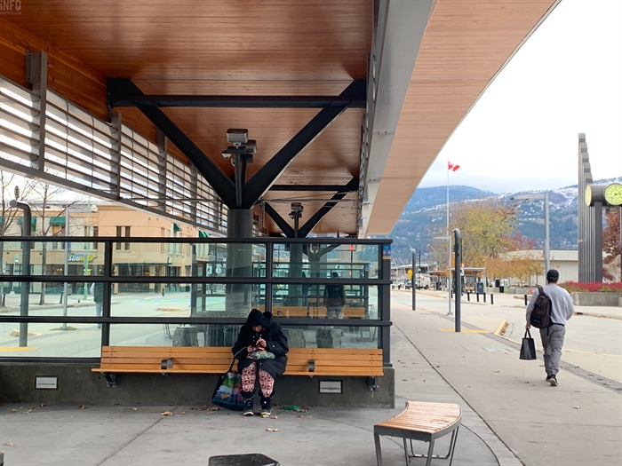 People waiting for the bus at a bus shelter in downtown Kelowna.