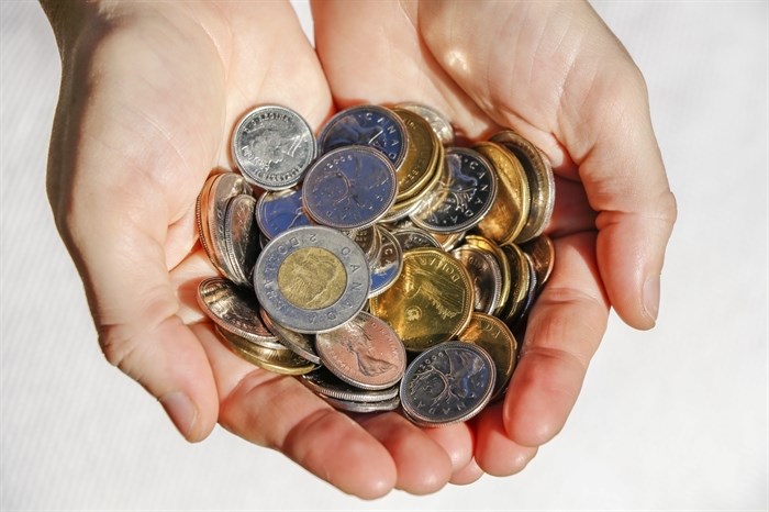 iN NUMBERS: Living wages get further from the minimum wage in B.C. | iNFOnews.ca Hands hold numerous Canadian coins.