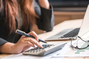 A woman at a desk with a calculator and laptop.