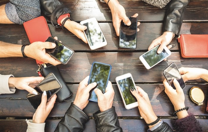 Multiple people holding their phones in their hands.