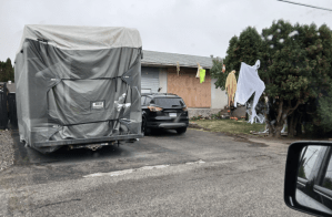 A boarded up house with Halloween decorations in the front yard.