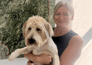 A blonde woman awkwardly holds a dog.